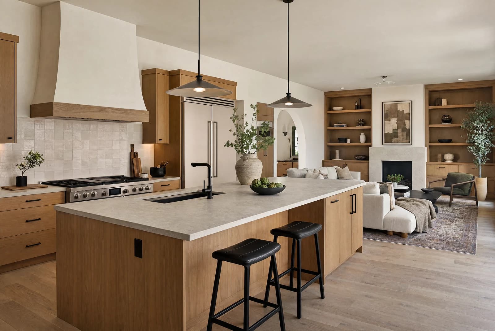 Warm open kitchen and living remodel concept with oak cabinetry, stone island, black pendants, and natural light.